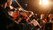 A classical musician, elegantly dressed, playing the violin at an indoor concert venue, audience in soft focus background