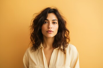 Wall Mural - Portrait of a beautiful young woman looking at camera over yellow background