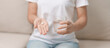 © Jo Panuwat D - woman hand holding medicine painkiller pill and water glass on the sofa at home, taking for headaches,  stomach ache, Diarrhea Pain from food poisoning, Endometriosis, Hysterectomy and Menstrual