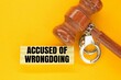judge's hammer, iron handcuffs and sticks with the words accused of wrongdoing. the concept of accusation of wrongdoing.