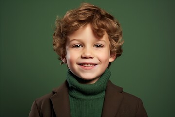 Portrait of a cute little boy in warm clothes on a green background.