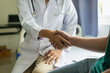 © ArLawKa - Doctor and patient shaking hands in the office, they are sitting at desk, hands close up A close - up handshake between a doctor and a patient in a medical office with clean