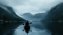  A Person Paddling A Kayak On A Lake In The Middle Of A Foggy Day With Mountains In The Distance And Fog Rolling In The Air Over The Water.