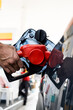 Refueling car with gasoline at gas station. Man hand grips a gasoline fuel nozzle at the refuel gas station station.