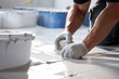 © Rainbow Kuma - A close-up of hands carefully placing a ceramic tile onto a freshly applied mortar bed on a bathroom floor