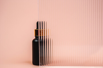 Hair oil is behind glass. Massage oil on a pink background. A bottle of cosmetics.