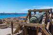Restored bronze cannon of the Castle of Saint George with the view of Lisbon, the 25 April suspension bridge and the sculpture of the religious monument of the National Sanctuary of Christ the King.