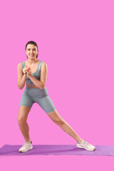 Sticker - Young woman in sportswear training on mat against purple background