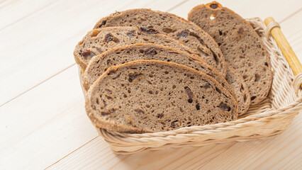 Bread in a wicker wooden plate, on the table, close-up. Healthy food, bread with raisins from dough