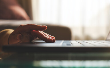 Closeup image of a hand working and touching on laptop computer touchpad at home