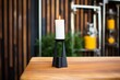 a tall, black candle holder with an unlit pillar candle