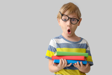 Poster - Surprised little boy in eyeglasses with books near grey wall