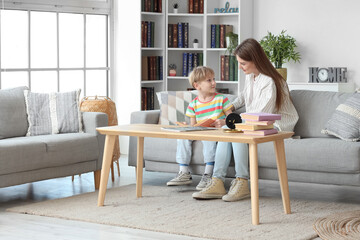 Poster - Little boy with his mother reading book on sofa at home