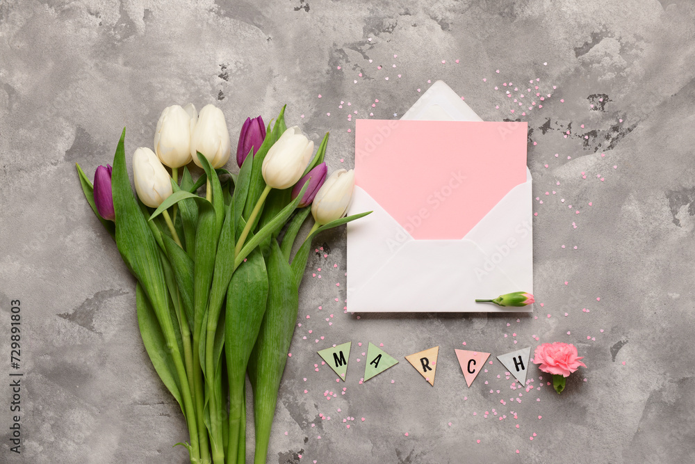 Envelope with blank card and tulip flowers on grey grunge background. International Women's Day celebration