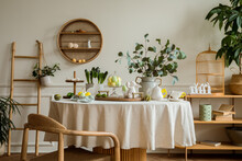 Warm And Spring Dining Room Interior With Easter Accessories, Round Table, Vase With Green Leaves, Cake, Colorful Eggs, Rabbit Sculpture And Personal Accessories. Home Decor. Template.