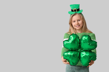 Poster - Cute little girl in leprechaun hat with air balloon in shape of clover on grey background. St. Patrick's Day celebration