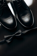 Men's Accessories Of The Groom Black Leather Shoes And A Bow Tie On A Black Table