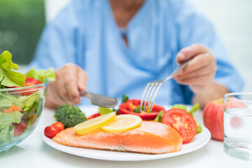 Asian elderly woman patient eating salmon steak breakfast with vegetable healthy food in hospital.