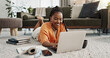 © Coetzee/peopleimages.com - Laptop, smile and woman typing on the floor in the living room of modern apartment for research. Technology, happy and young African female university student studying on a computer in lounge at home