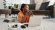 © Coetzee/peopleimages.com - Laptop, coffee and woman on the floor in living room of modern apartment reading information. Technology, relax and young African female student study and drink latte on computer in lounge at home.