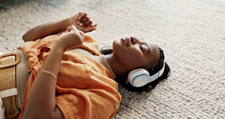 Poster - Headphones, relax and young woman on the floor in the living room listening to music or radio at modern apartment. Dancing, smile and young African female person streaming song in the lounge at home.