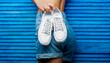 © Yevhen - Woman holding a pair of white shoes. Girl with a beautiful waist in jeans shorts. Girl with a beautiful figure in jeans shorts and white shoes. Girl hold a pair of shoe. Woman holding shoes