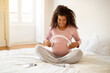 Pregnant Woman Holding Headphones Near Belly, Playing Melody To Baby In Womb