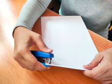 An office worker is stapling papers at her desk. Closeup image. Concept of personal assistant or administrative work