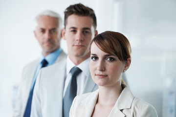 Poster - Portrait of three corporate business people , standing in a row and in broad room. Smiling friendly group of three business partners of different age private company staff posing for office