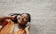 © Coetzee/peopleimages.com - Home, music and black woman on a couch, headphones and streaming audio in a living room. African person on a sofa, apartment or girl with headset, listening to sound and relax with happiness or song