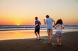 © Irina Schmidt - Three kids silhouettes running and jumping on beach at sunset. happy family, two school boys and one little preschool girl. Siblings having fun together. Bonding and family vacation.
