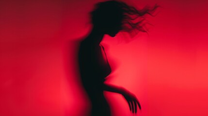 Wall Mural - Female blurred silhouette on a red background. Elegant outline of a woman in motion out of focus