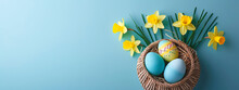 Colorful Easter Eggs In A Basket With Daffodils On Pastel Blue Background, Banner With Copyspace, Top View