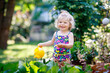 © Irina Schmidt - Cute little baby girl in colorful swimsuit watering plants and blossoming flowers in domestic garden on hot summer day. Adorable toddler child having fun with playing with water and ca