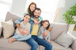 © deagreez - Photo of four persons sit on couch guy hugging girls toothy smile enjoy free time weekend hone indoors
