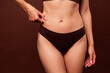 Leinwandbild Motiv Cropped photo no filter of attractive young woman clamp belly stomach folds dressed stylish underwear isolated on brown color background