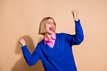 Portrait of delighted crazy girl raise fists shout yes hooray accomplishment isolated on beige color background