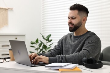 Poster - E-learning. Young man using laptop during online lesson at white table indoors