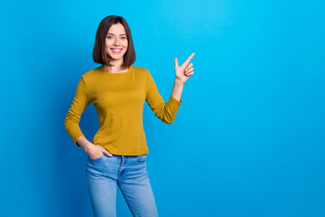 Wall Mural - Photo of cheerful positive lady dressed shirt pointing finger empty space isolated blue color background