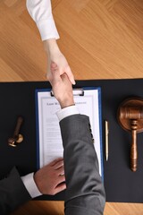 Wall Mural - Notary shaking hands with client at wooden table, top view