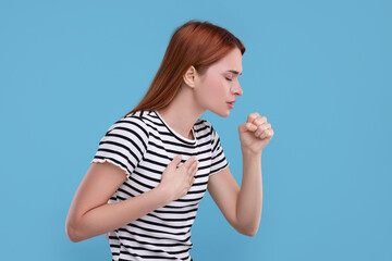 Poster - Woman coughing on light blue background. Cold symptoms