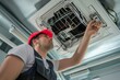 A technician examines the filters of a ceiling air conditioner.