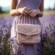 A woman is holding a crochet purse amidst a field of lavender
