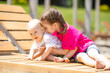 © Irina Mikhailichenko - Cute children little girl and newborn baby boy sitting on wooden beach chair near the sea during family vacation. Summer travel concept.