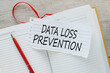 DATA LOSS PREVENTION. torn paper with text on a yellow notepad. red bookmark for notebook