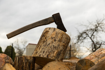 An ax for splitting firewood stuck into a stump for chopping wood.