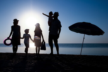 Canvas Print - A Happy family by the sea at sunset in travel silhouette in nature