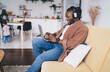 © BullRun - Positive black man in headphones using laptop while working at home