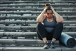 © wolfhound911 - Overweight woman tired after workout. Fat chubby girl in sportswear with fitness mat sits down on stone steps outside gym, holds her head, feels sad and exhausted. Sport, fatigue, frustration concept