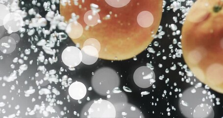 Wall Mural - Composition of white spots of light over oranges floating in water on black background